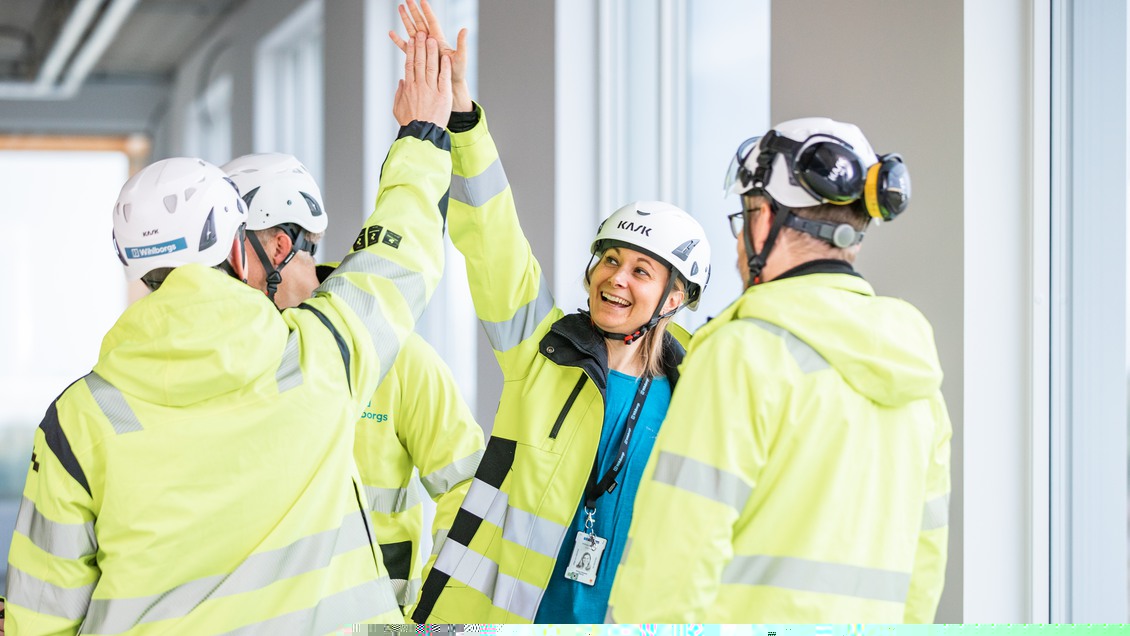 Flera personer på en byggarbetsplats gör en high five