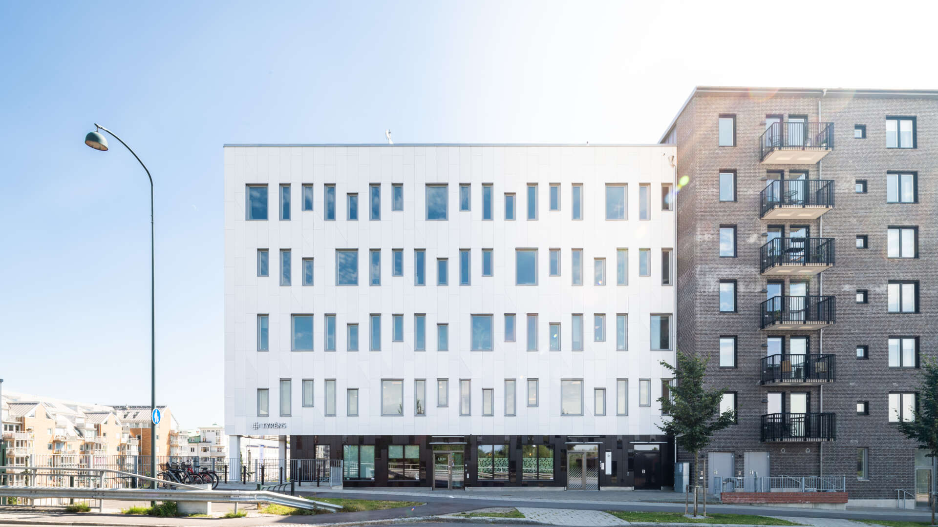 Vit och grå modern kontorsbyggnad i flera plan, Raffinaderiet 5 (Sockerbiten), fastighet med moderna kontorslokaler på Kung Oskars väg 11 vid Lund C.